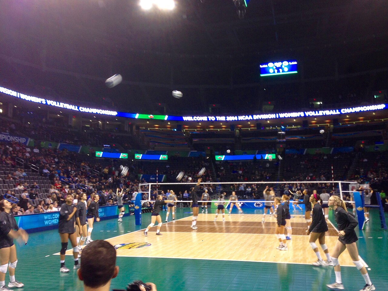 Penn State players in black warm-up shirts pepper volleyballs across a teal-bordered championship court under a ribbon board reading Welcome to the 2014 NCAA Division I Women's Volleyball Championship.